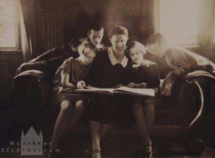Muter mit vier Kindern, ein Buch anschauend