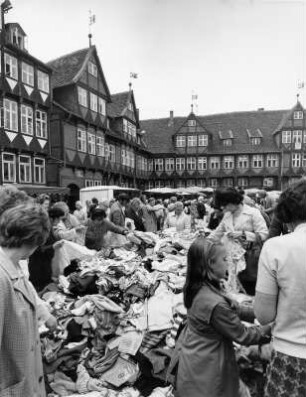 Wolfenbüttel. Wochenmarkt auf dem Marktplatz. Kauflustige wühlen in Textilien. Im Hintergrund historische Wohngebäude im Backsteinstil
