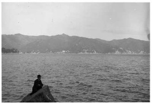 Genua/ Italien: In der Bucht, einzelner Herr auf einer Felsklippe sitzend