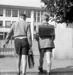 Zwei Schüler mit Schulranzen und Aktentasche auf dem Schulweg
