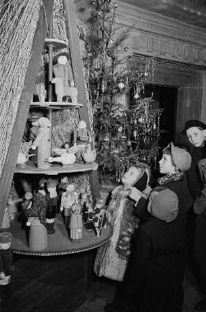 Vier Kinder vor einer Weihnachtspyramide in der Ausstellung weihnachtlicher Volkskunstarbeiten des Stadtgeschichtlichen Museums