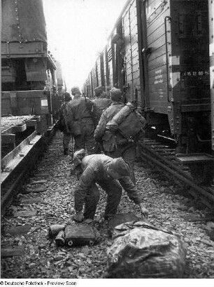 Deutschland . Truppenübungsplatz Klietz. Nationale Volksarmee - Landstreitkräfte. Truppenverlegung per Eisenbahnmarsch. Soldaten zwischen zwei Militärzügen (links Flachwagen mit Militärtechnik, rechts Mannschaftswagen)