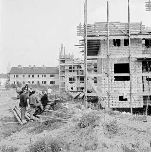 Wohnungsbau: Wohngebiet Kellerberg-Süd: Wohnblocks im Bau: Rohbauten der Neuen Lübeck-Südholsteinischen Baugenossenschaft, teilweise mit Gerüsten: links Anhänger mit Brettern: Arbeiter beim Entladen