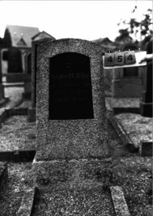 Grabstein 454 (Index: 99797544) Material: Granit, Basaltplatte Zustand: leicht verwittert Maße HxBxT: 141x58x27 cm Beschreibung: Stele, Segmentbogenabschluß, Sockel: Grabstein 454