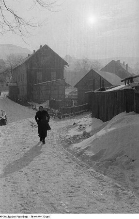 Blick auf eine Frau vor verschneiten Wohnhäusern