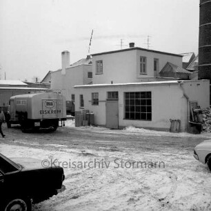 Meierei-Genossenschaft Trittau eGmbH Zweigwerk: Manhagener Allee: Hofansicht mit Betriebsgebäuden: im Winter: rechts Schornstein: links Tanksammelwagen mit Aufschrift "Mili Eiskrem": im Vordergrund links Heck von Pkw