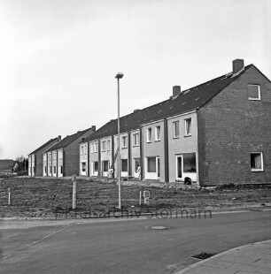 Mühlenstraße / vorne Ecke Stormarner Straße: Reihenhäuser: vor Fertigstellung: Handwerker bei Arbeiten an Fassade, Leitern, Schubkarre: Straßenlampe