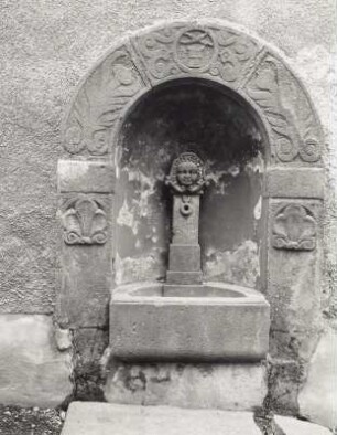 Brunnen mit Portalabschluss und drei Steinköpfen