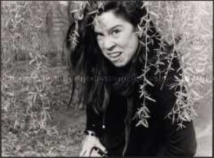 Grimasse schneidende junge Frau unter einem Baum (Sonderthema: Ein Bild von mir - Selbstporträts und Selbstdarstellungen)