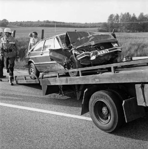 B 208: Kurve bei Westerau: Verkehrsunfall: Zusammenstoß von zwei Pkws: ein Unfallwagen mit eingedrückter Front auf Plattform von Abschleppwagen: dahinter Feuerwehrleute: Zaun, hinten Feld, im Hintergrund Wald