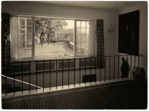 Wohnhaus Dr. Scheufelen, Stuttgart: Flur Hauptgeschoss mit nach unten führender Treppe und Blick in den Garten mit den Kranichskulpturen
