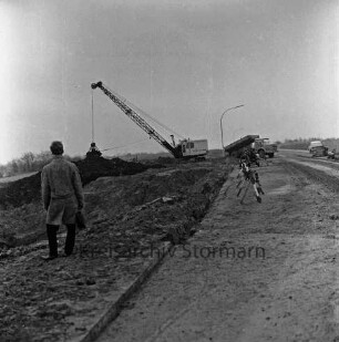Industriestraße: Absackung eines Teilstücks: in der Mitte Absperrung und Erdhaufen: dahinter Bagger und Lkw: hinten rechts Pkw: vorn links Mann