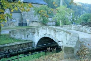 Gesamtansicht der alten Steinbogenbrücke über dem Dorfbach