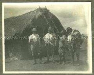 Deutsche Offiziere mit Askari vor einer Hütte
