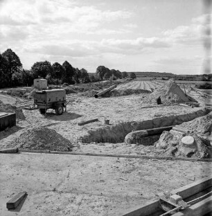 B 75 zwischen Hamberge und Ratzbek: Straßenbau: Bau einer Brücke über die Autobahn A 1: links hinten alte Straßenführung: Blick auf die neue Trasse: vorn Baumaterial: links Bauwagen, rechts Sandhügel