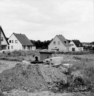 Neubausiedlung: Einfamilienhäuser nach Fertigstellung: im Vordergrund Erdhaufen und Baumaterial