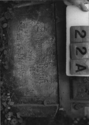 Grabstein 22 (Index: 100109168) Material: Sandstein Zustand: Schrifttafel fehlt, Sockel sehr stark verwittert, Stele gehört nicht zum Sockel Maße HxBxT: 131x64x29 cm Beschreibung: Stele auf Sockel, Schrifttafel eingesetzt (fehlt) mit Rahmen Besonderheit: Aufgrund der Register kommt keine andere Person infrage.: Grabstein 22A