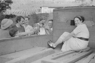 Frauen : Frauen stehen an der Ladefläche eines Lastkraftwagens; eine von ihnen zielt mit einer Schusswaffe.