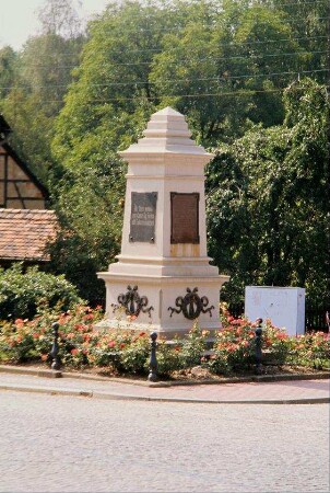 Obelisk in einer Rabatte mit Tafel "Die Toten mahnen zum Kampf für Frieden und Völkerfreundschaft"