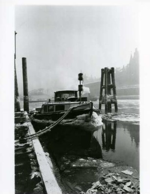 Hamburg. Winter im Hafen. Ein vereister Schlepper liegt vertäut am Kai. Das Hafenbecken ist bereits teilweise zugefroren