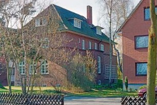 Struhbarg 12: giebelständiges Wohnhaus aus Backstein mit umlaufendem Gesims: Straßenfront mit Rundbogen-Sprossenfenstern: Traufseite mit Eingangsvorbau, Rankgitter: Vorgarten: vorne Jägerzaun, Parkplatz