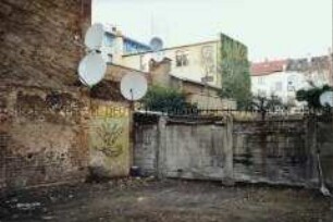 Blick in einen Hinterhof mit Parabolantennen und Graffiti (Altersgruppe 18-21)
