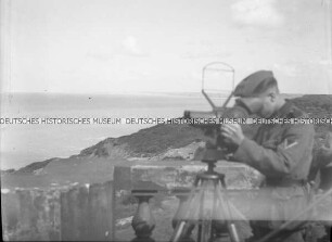 Soldat sieht durch ein Flak-Fernrohr (an der französischen Kanalküste)