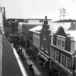 Hindenburgstraße: Wohn- und Geschäftsgebäude sowie Passanten in der Fußgängerzone im Winter, im Hintergrund das Kaufhaus Nickel, Blick Richtung Osten