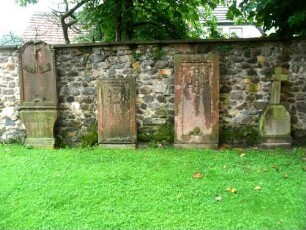 Kirchhof im Osten - Kirchhofmauer mit aus dem im 18 Jh aufgelassenen Kirchhofhof aufgestellten Grabsteinen (Renaissance bis Barock)