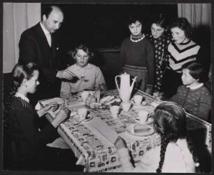 Der Lehrer zeigt den Schülerinnen, wie sie den Kuchen mit einer Gabel essen