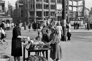 Berlin, Alexanderplatz. Frau an einem Verkaufstisch mit Spielzeug. Im Hintergrund das zerstörte Hertie-Kaufhaus