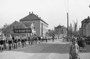 Arbeitersportlerinnen und Arbeitersportler mit dem Transparent "Für Arbeit und Brot!" vor der Drogerie Thürmer in Heidenau