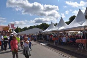 Bad Oldesloe: Kindervogelschießen: Exer, Blickrichtung Osten: Festplatz mit Besuchern: rechts kleines Festzelt und im Hintergrund großes Festzelt, links Imbissstand: 13. Juli 2023