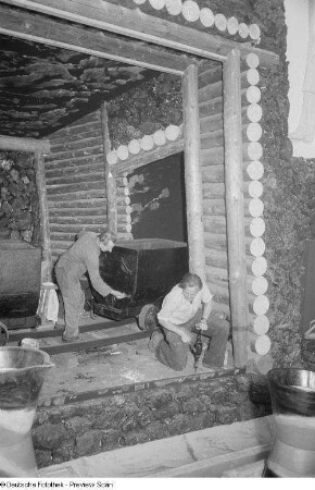 Arbeiter während des Aufbaus eines Messestandes in Form eines Stollens (Bergwerk) mit Loren