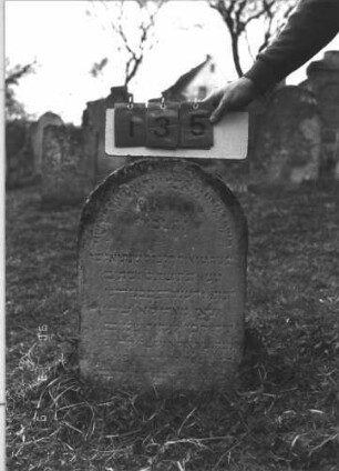 Grabstein 135 (Index: 99786144) Zustand: leicht verwittert, leicht eingesunken Maße HxBxT: 70x40x11 cm Besonderheit: kulturhistorisch wertvoll / künstl.-formale Gründe (Inschrift): Grabstein 135