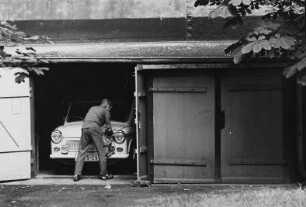 Autopflege : Mann putzt einen in einer Garage stehenden PKW "Trabant"