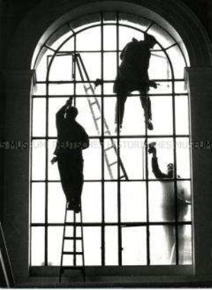 Drei Fensterputzer säubern ein großes Fenster