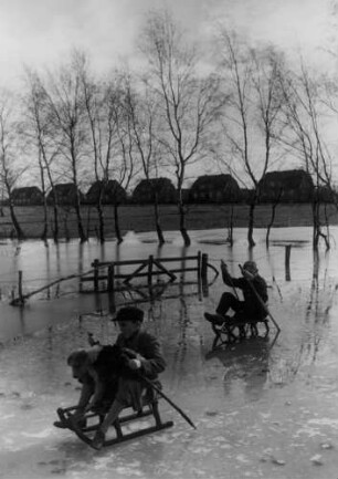 Auf den vereisten Wiesen fahren Kinder Schlitten; 1940