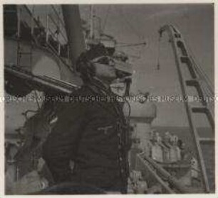 Wehrmachtssoldaten, Schlachtschiff, Befehlsübermittler bei einem leichten Flakgeschütz, Als Ausguckposten gegen feindliche Flugzeuge trägt der Matrose eine Sonnenbrille.