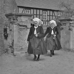 Frauen in Spreewälder Kirchgangstracht auf dem Weg zur Kirche in Dissen. : Žony w Błótowskej kemšacej drasće ducy do cyrkwje w Dešnje.