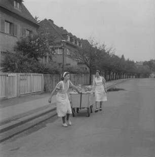 Zwei Kindergärtnerinnen mit einem Bollerwagen mit Kleinkinder