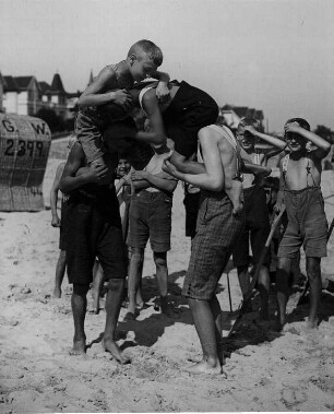 Am Strand. Auf Schultern sitzende Jungen beim Ringkampf