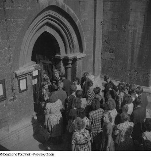 Besucher vor einem Kirchenportal