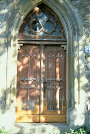 Kirche: spitzbogiges Portal mit zweiflügeliger Holztür