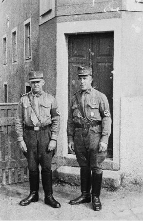 Angehörige der SA (Sturmabteilung) vor einem Hauseingang : auf den Mützen ist noch die bis 1936 getragene erste Form des Parteiadlers zu sehen