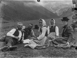 Gruppenportrait : Portrait dreier Frauen und zweier Männer bei der Mittagsrast auf einer Alp im Vinschgau. Im Hintergrund liegt ein Hund.