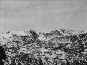 Bergpanorama : Eine Berglandschaft mit verschneiten Gebirgszügen im Hintergrund. Im Vordergrund sitzen drei Mitglieder des Transkontinentalen Geographenkongresses