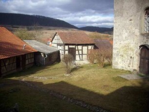 Kirchhof im Nordwesten von Süden mit Langhaus (romanisch gegründet-verändert) über Giebelseite sowie Fachwerk-Gaden in Übersicht