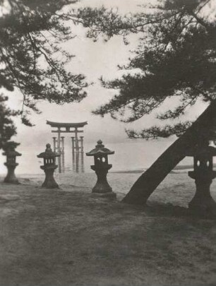 Hatsukaichi, Insel Miyajima, Japan. Großer Torii vor dem Itsukushima-Schrein (seit 1996 UNESCO-Weltkulturerbe), bei Flut im Seto-Inlandsee. Blick vom Strand über steinerne Heilige Laternen