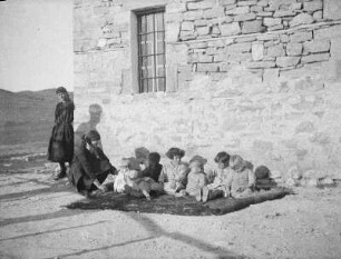 Kinder : Kinder mit zwei Frauen vor einem Haus